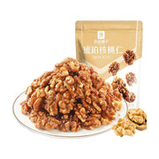 良品铺子琥珀核桃仁，盘中堆叠的裹糖核桃仁，背景为商品包装袋。