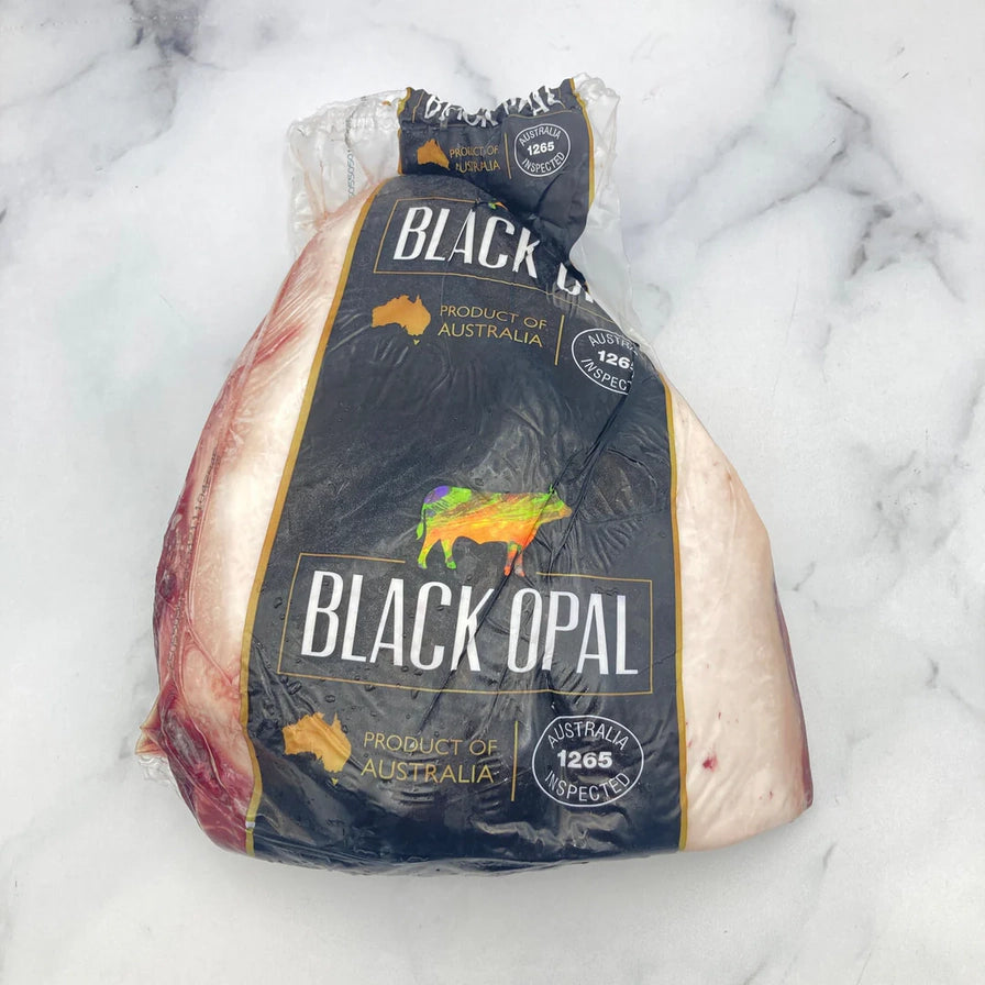 Black Opal 黑蛋白石和牛保乐肩整块装，放置在大理石纹理背景上，展示真空包装状态。