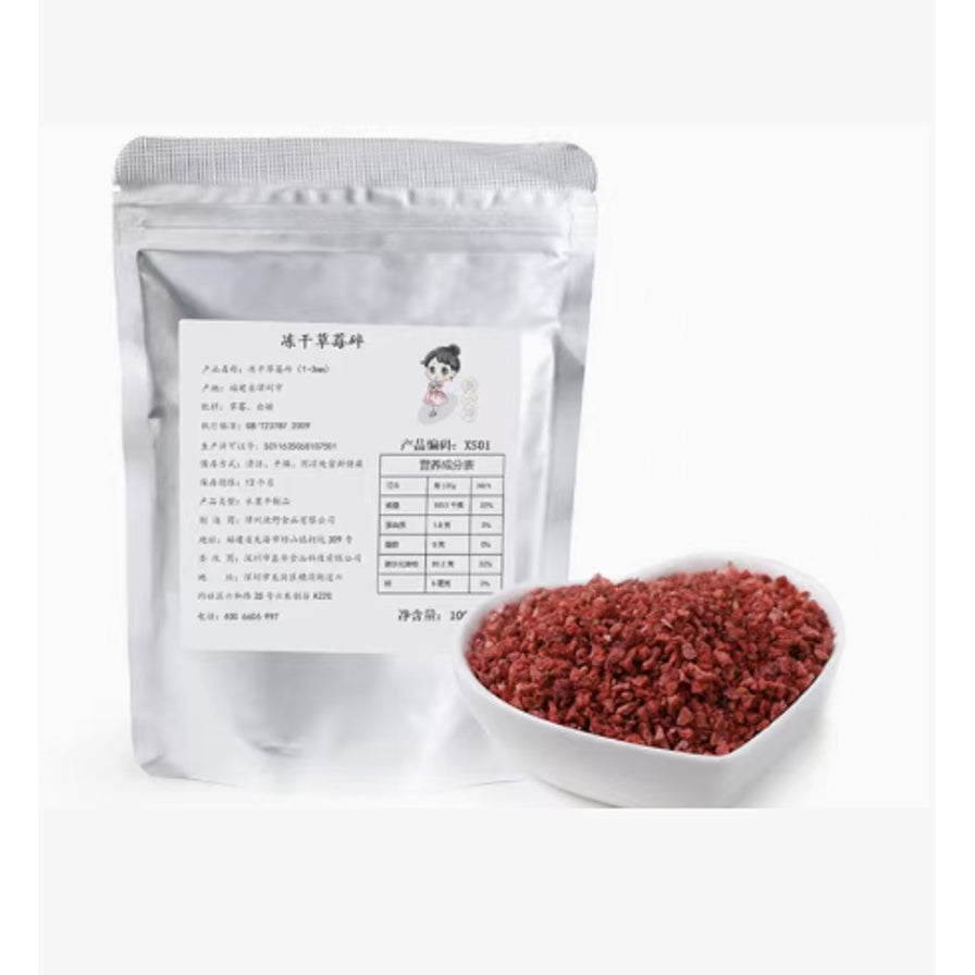 银色密封包装袋的冻干草莓碎，旁边放着一碗装满红色草莓颗粒的心形小碗。