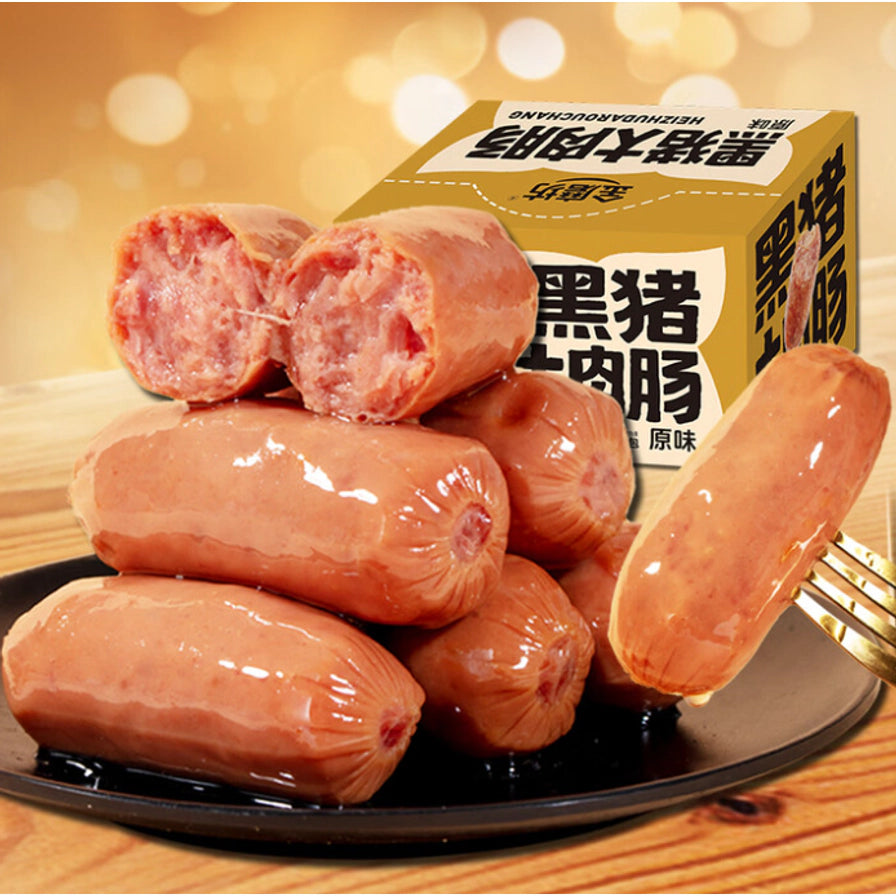 金磨坊黑猪大肉肠原味，背景为木质桌面，展示叉子叉起的一根香肠及盘中堆叠的香肠。