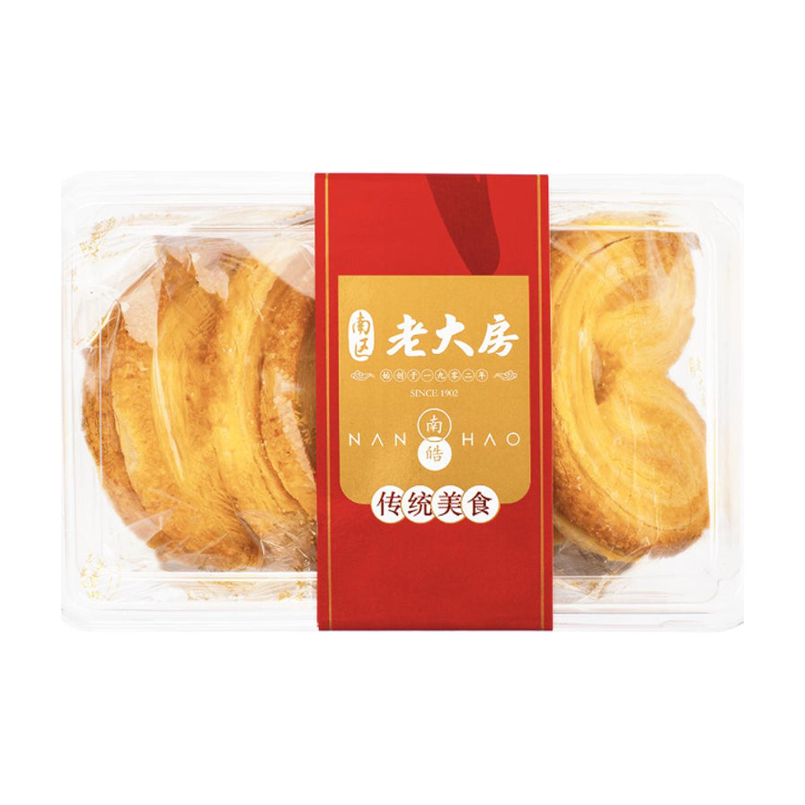 老大房蝴蝶酥透明盒装正面图，红色封条印有老字号品牌标识和传统美食字样，可见内部金黄酥脆的蝴蝶酥。