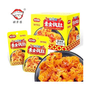 缺牙齿素金钱肚香辣味魔芋制品，包含黄色大包装盒、两个独立小包装袋以及一盘展示出的Q弹爽脆素金钱肚。