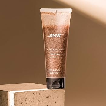 RNW 磨砂沐浴露软管特写，放置于米色石质台面上，背景为暖色调光影。