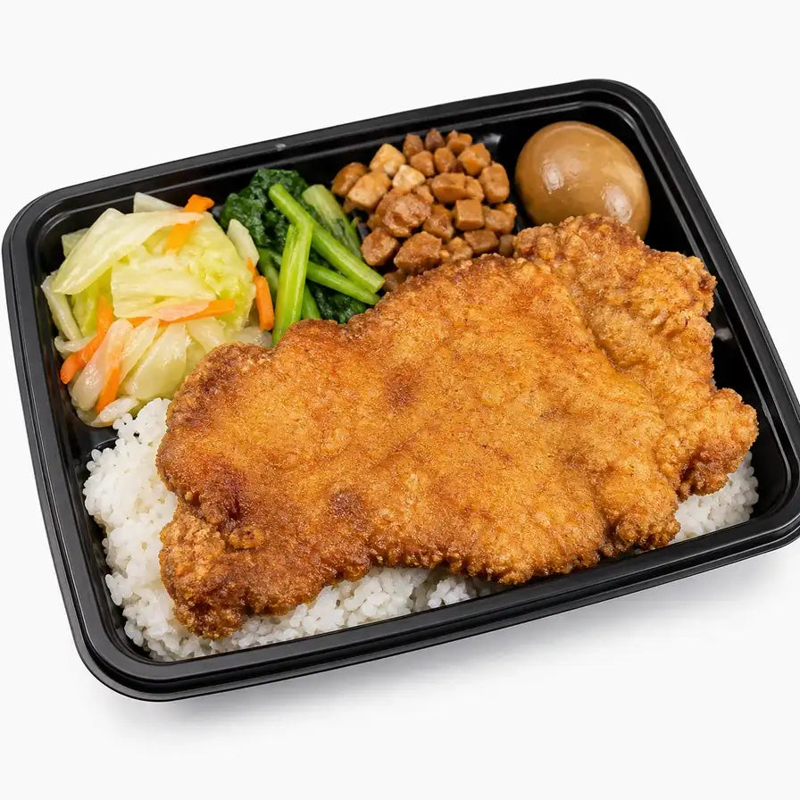 招牌厚切大排饭便当，包含一大块金黄酥脆的炸大排、白米饭、卤蛋、青菜和配菜，采用黑色外带餐盒盛装。