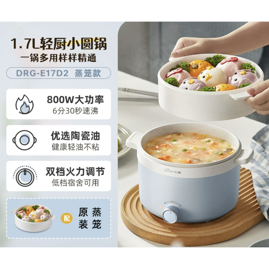 小熊电煮锅使用场景图，展示上层蒸笼内的卡通馒头和下层锅内的海鲜粥，左侧配有800W功率和陶瓷油内胆等卖点文字。